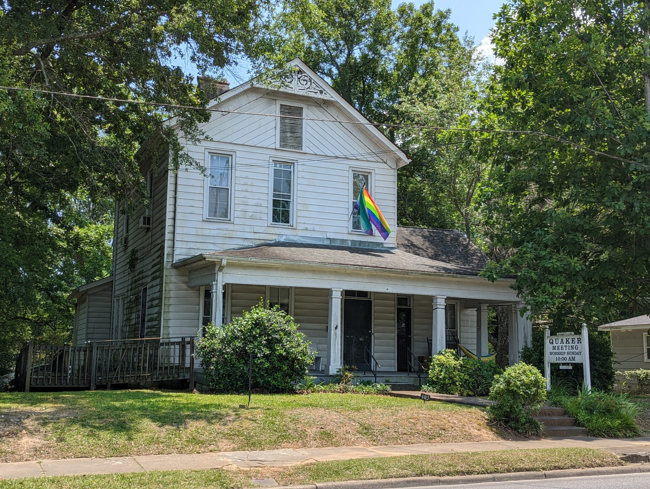 Photo of a white house with a rainbow pride flag in front